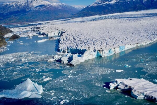 Glacier with icebergs in cold mountain landscape.