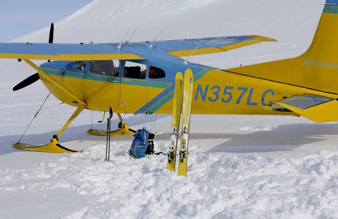 Yellow ski plane on snowy mountain landing.