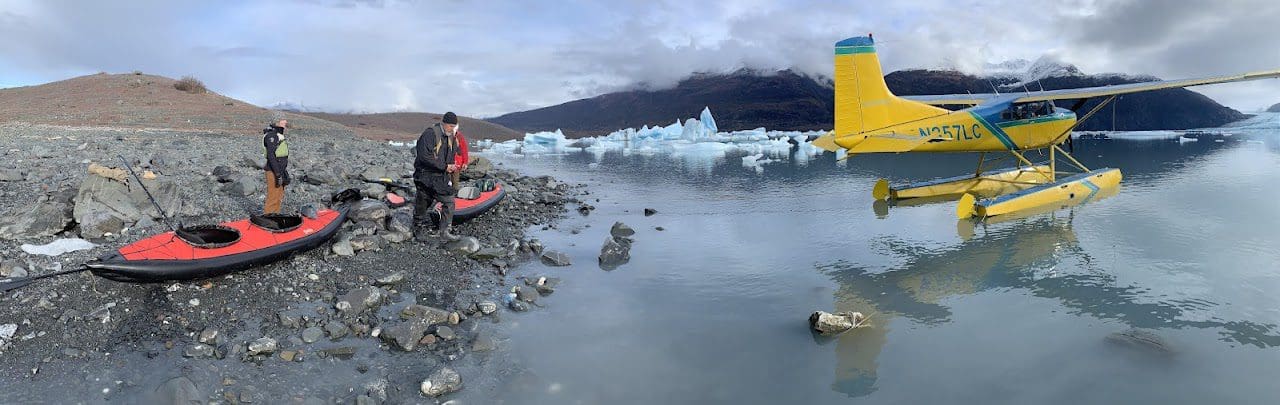 Seaplane and kayaks by icy mountain lake.