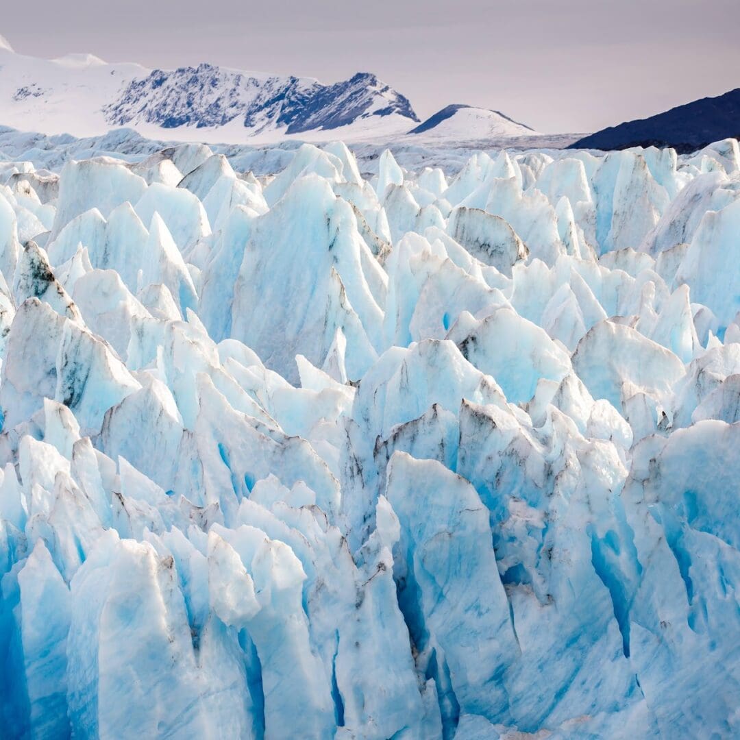 Jagged icy landscape with distant snow-covered mountains.