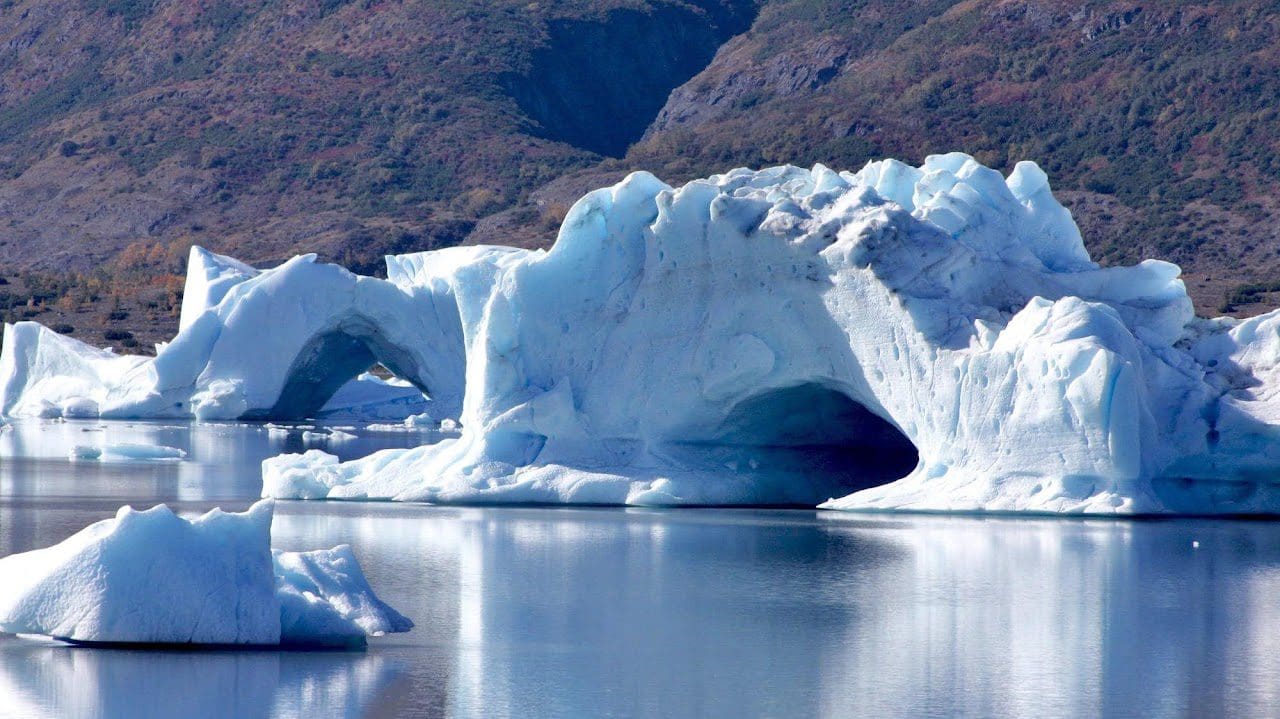 Icebergs floating in a calm lake.