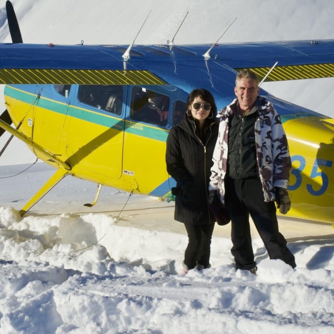 Two people standing beside a small plane.