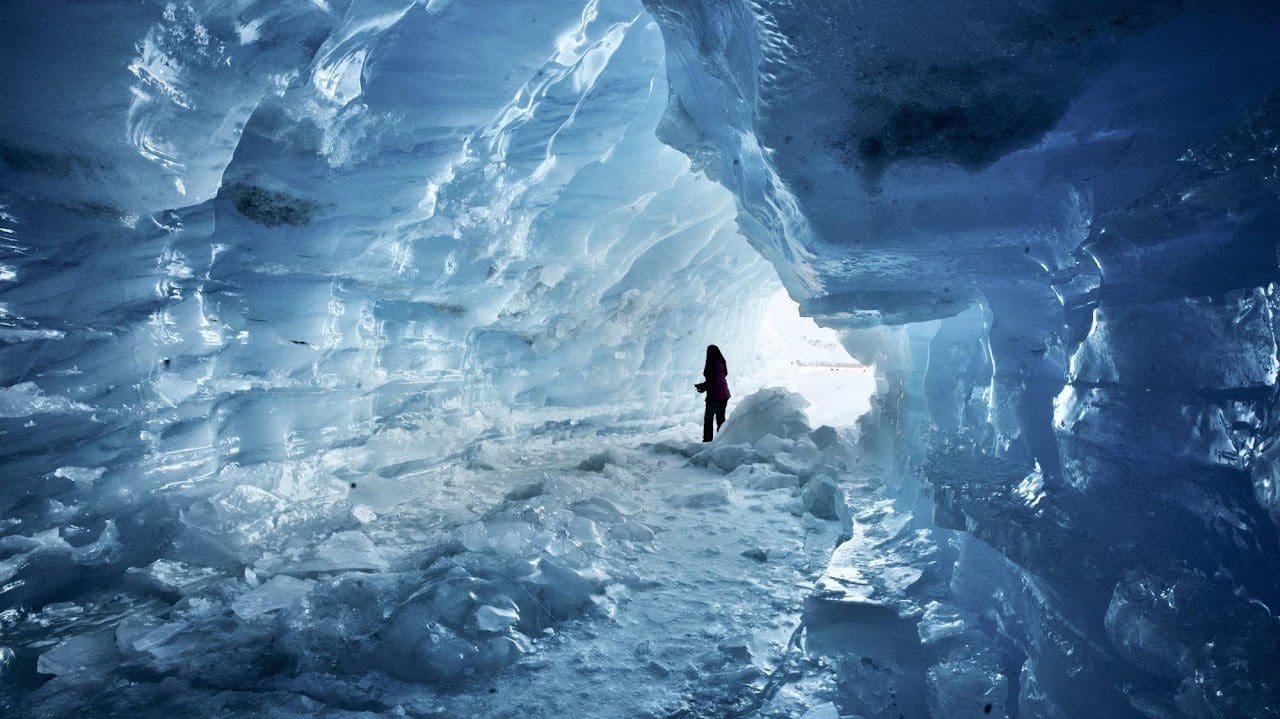 Person standing in icy cave passageway.