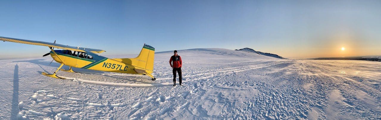 Small plane and person on snowy landscape.