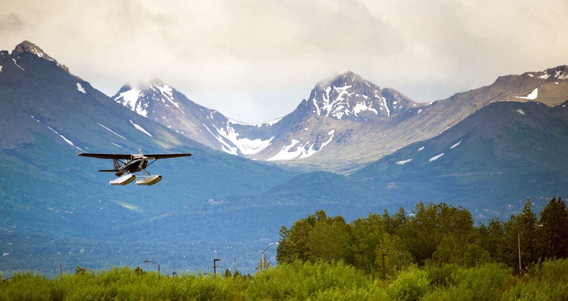 Seaplane flying near snow-capped mountains.