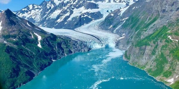 Mountain glacier flowing into turquoise lake.