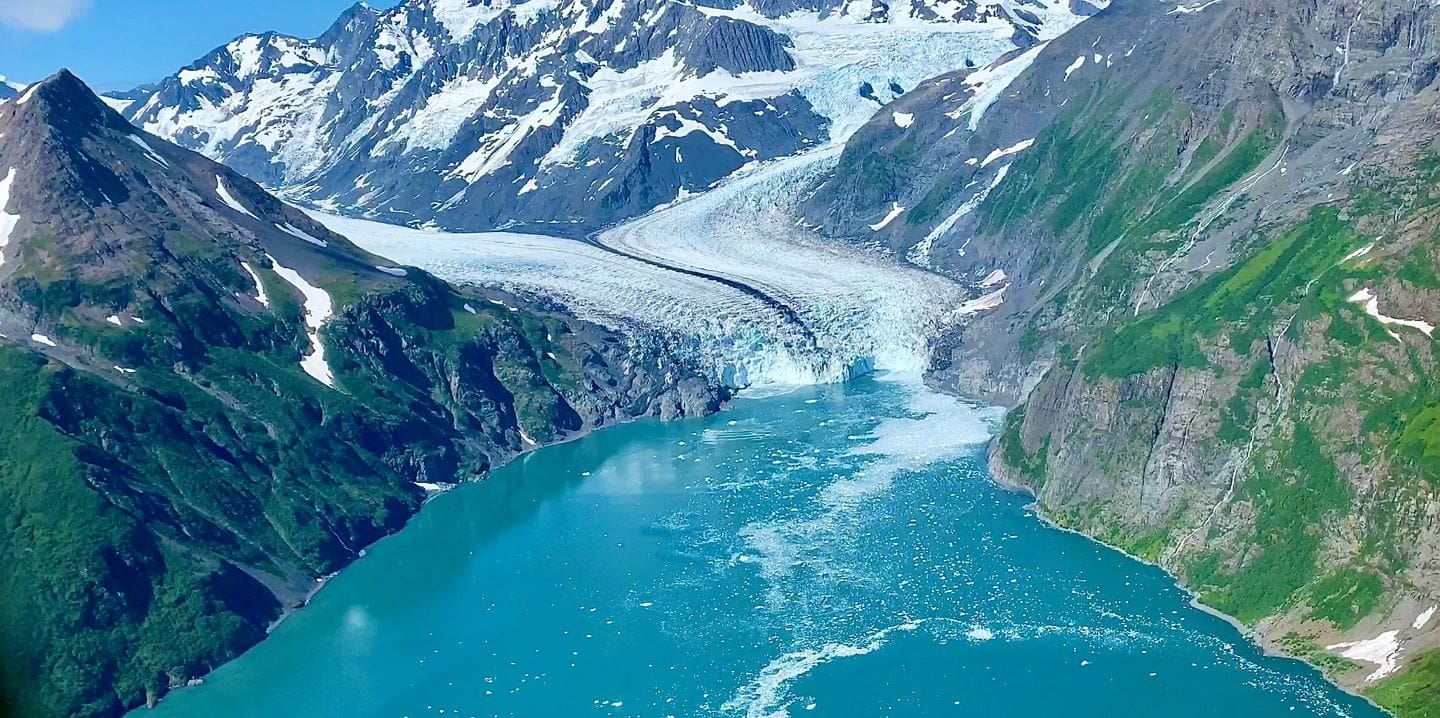 Mountain glacier flowing into turquoise lake.