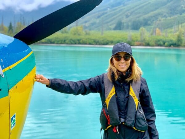 Person standing beside a seaplane near water.