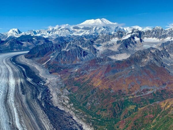 Snowy mountains and glacier under blue sky.