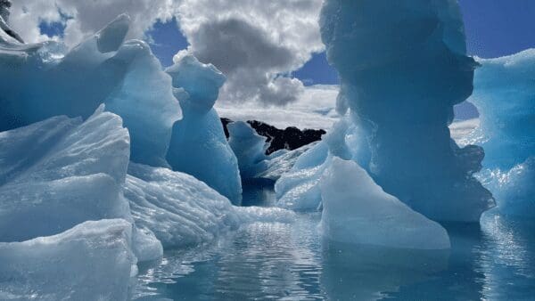 Blue ice formations under cloudy sky.