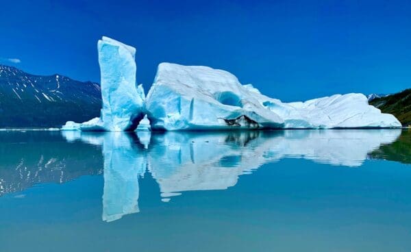 Iceberg reflecting on calm blue water.