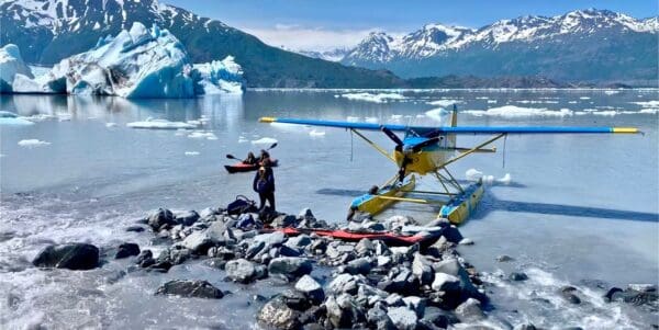 Seaplane and kayaks on icy mountain lake.