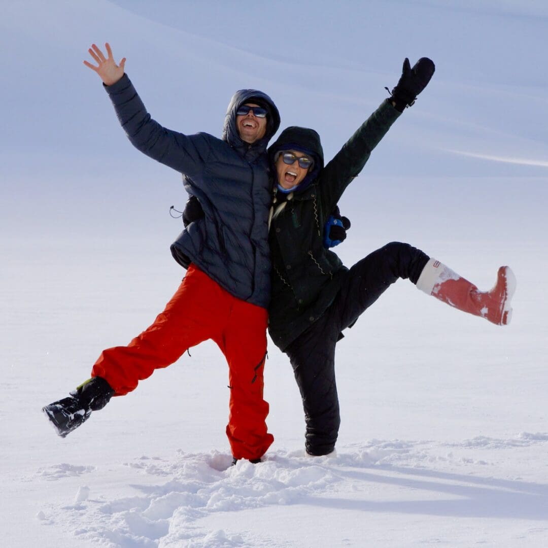 Two people joyfully posing in snowy landscape.