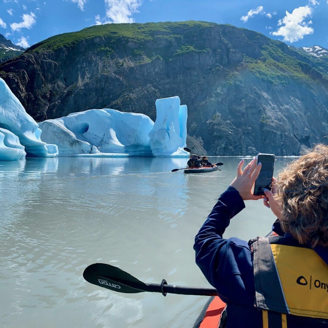 Untitled (1) Person kayaking near glacier, taking photo.
