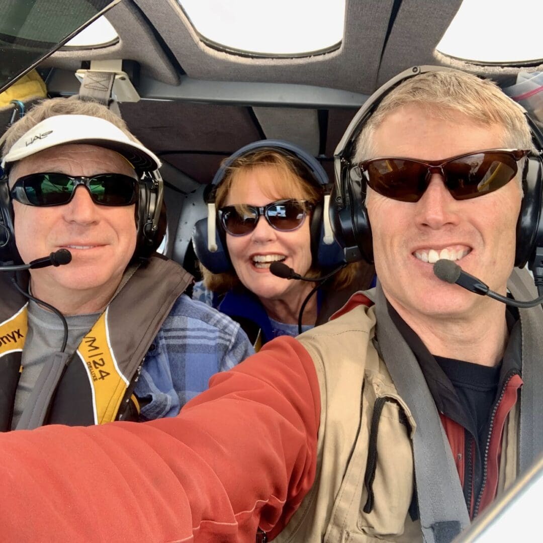 Untitled (2) Three people smiling inside an airplane cockpit.