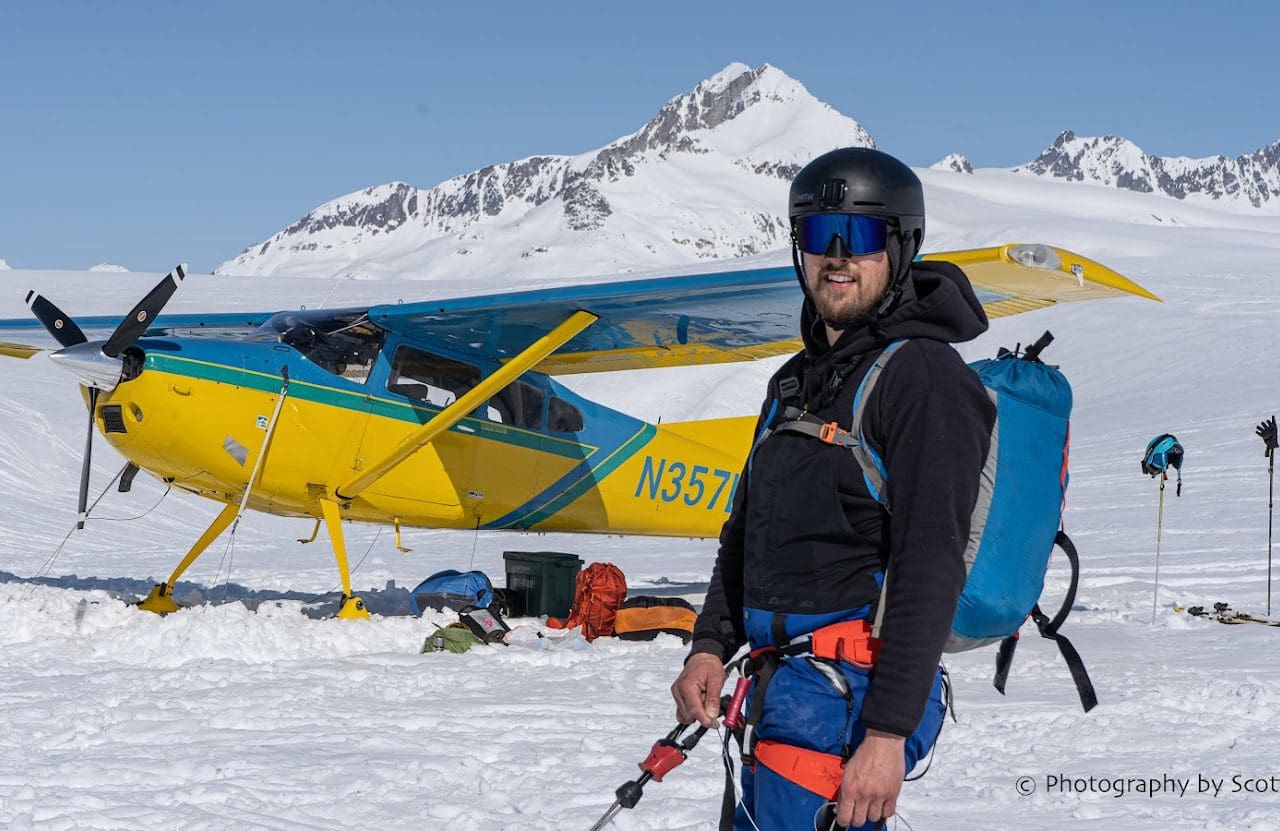 Man standing by plane on snowy terrain.