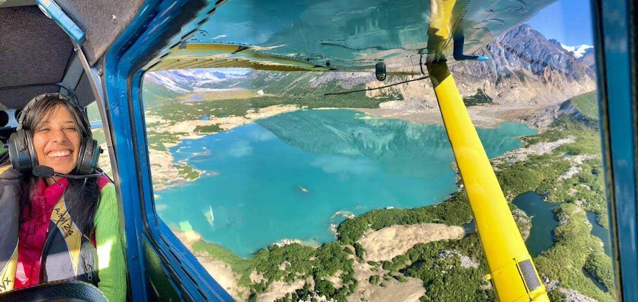 Untitled Woman smiling inside small airplane over lake.
