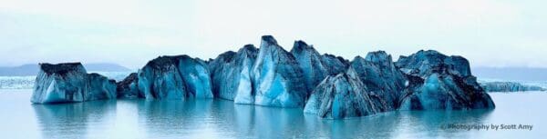 Blue icebergs floating on calm water.