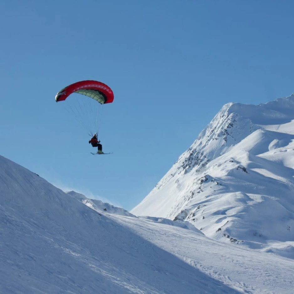Frame-1321315776-1 A person is flying in the air with a parachute.