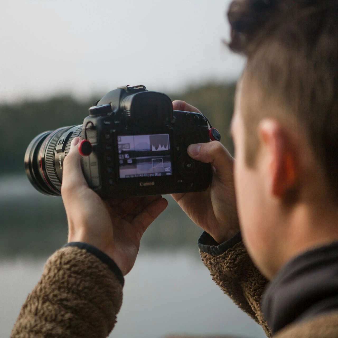 maxim-medvedev-fwxoAAknWe0-unsplash A man holding a camera taking a picture of the water.