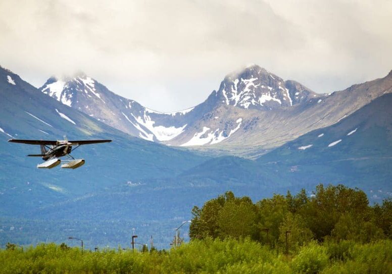 Seaplane flying near snow-capped mountains.