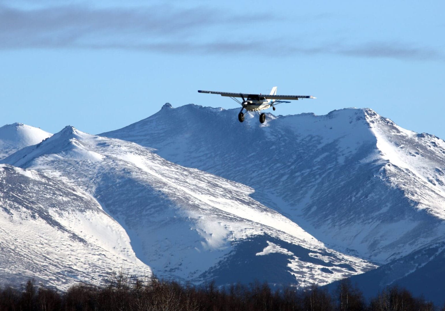 bush pilot landing plane Airplane flying over snowy mountain range.