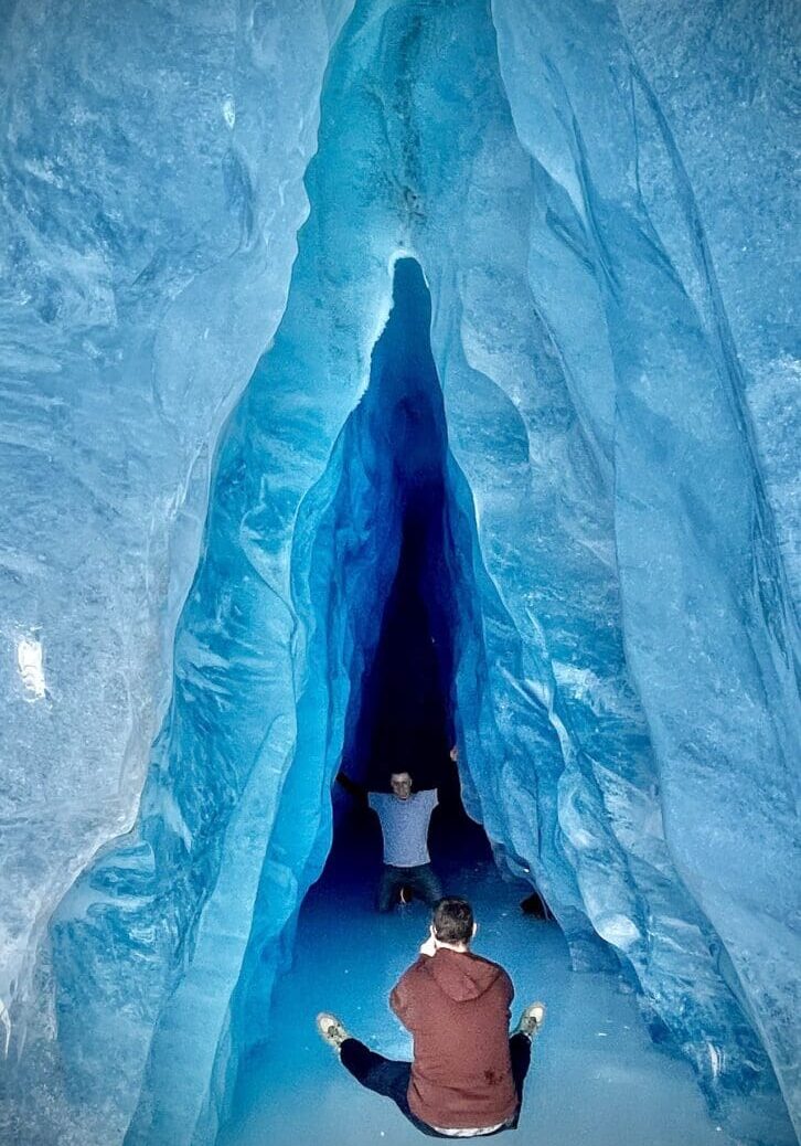 Untitled (3) People exploring narrow blue ice cave.