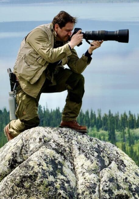 Untitled (5) Photographer on rock with telephoto lens.