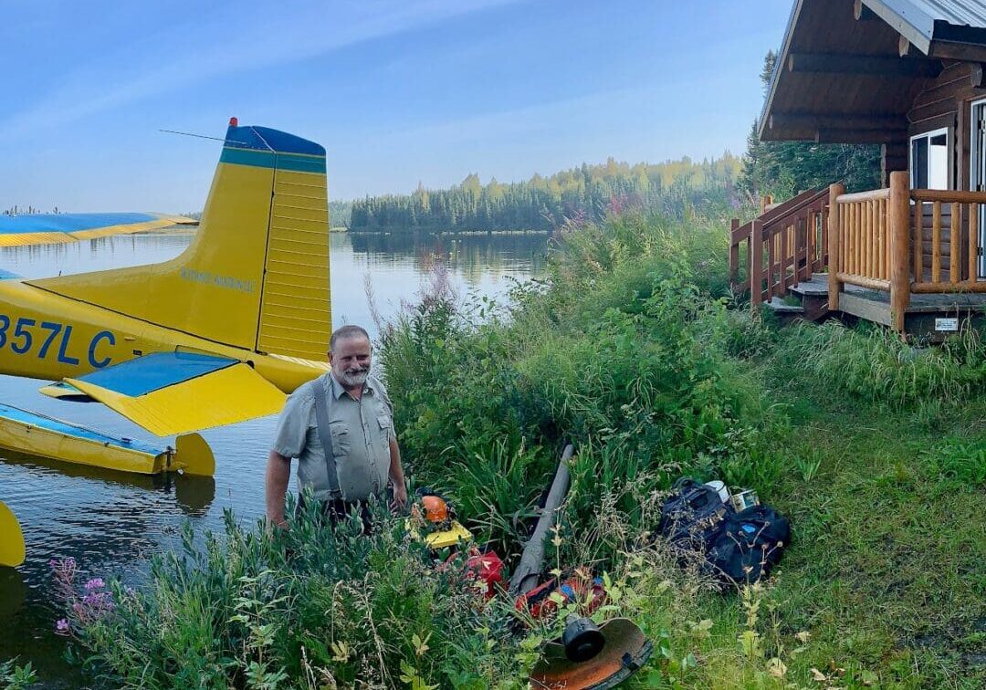 Untitled (9) Seaplane by cabin on lakeside with man.